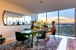 Ein moderner Essbereich mit großem Fenster, Blick auf die Stadt und einem Esstisch mit Stühlen.