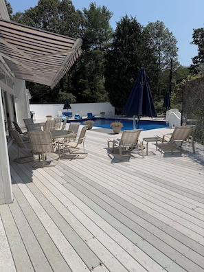 Eine Holzterrasse mit Gartenmöbeln und einem Swimmingpool.