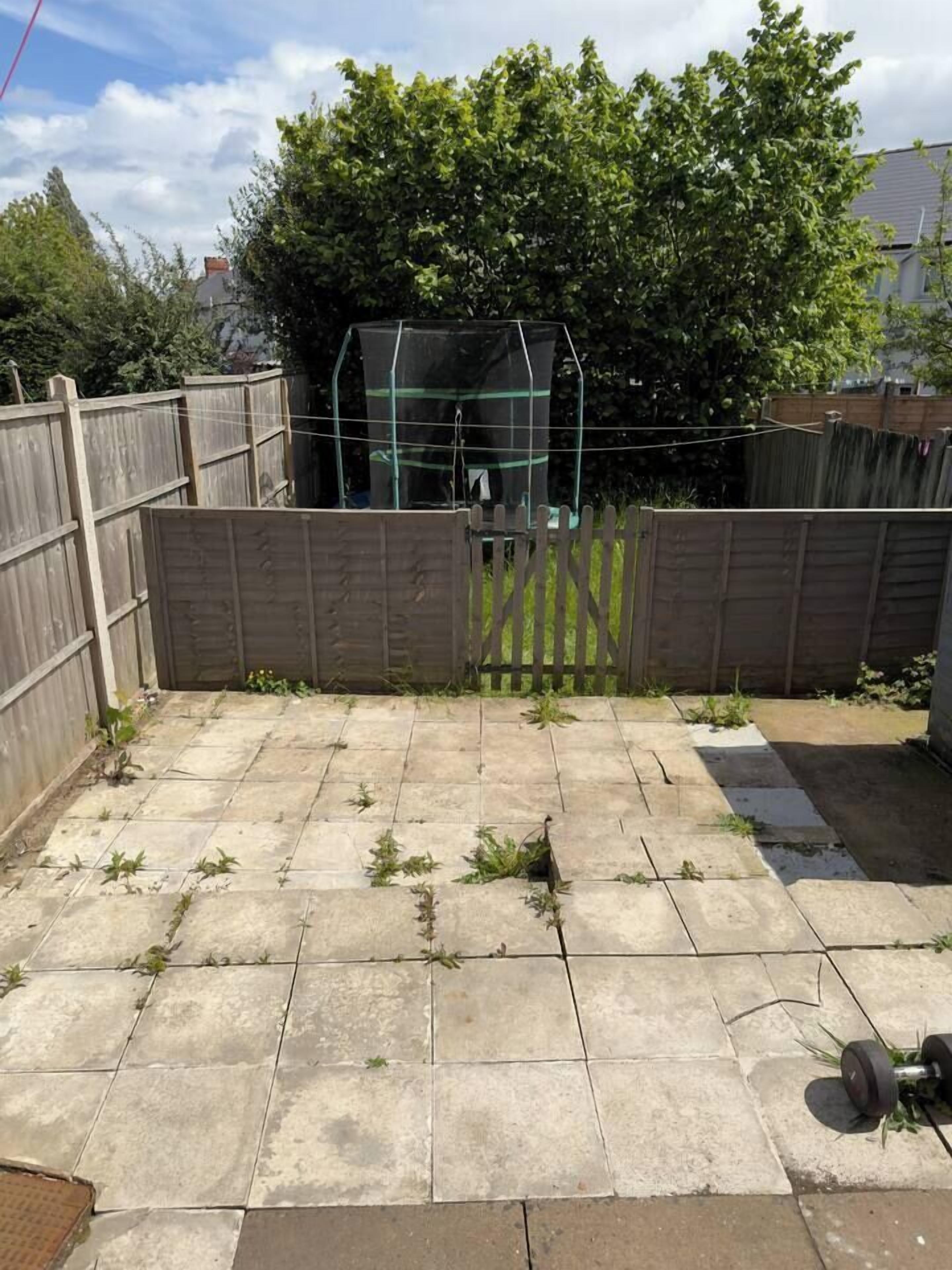 Ein Garten mit Holzzaun, grünem Busch und Metallkonstruktion.