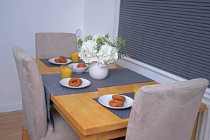 Ein Esstisch mit Frühstücksangeboten, darunter Gebäck und Saft, sowie eine Vase mit weißen Blumen.