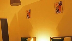 Una habitación de hotel con dos camas, una lámpara colgante y obras de arte en las paredes.