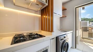 Una cocina moderna con estufa a gas, horno empotrado y lavadora.