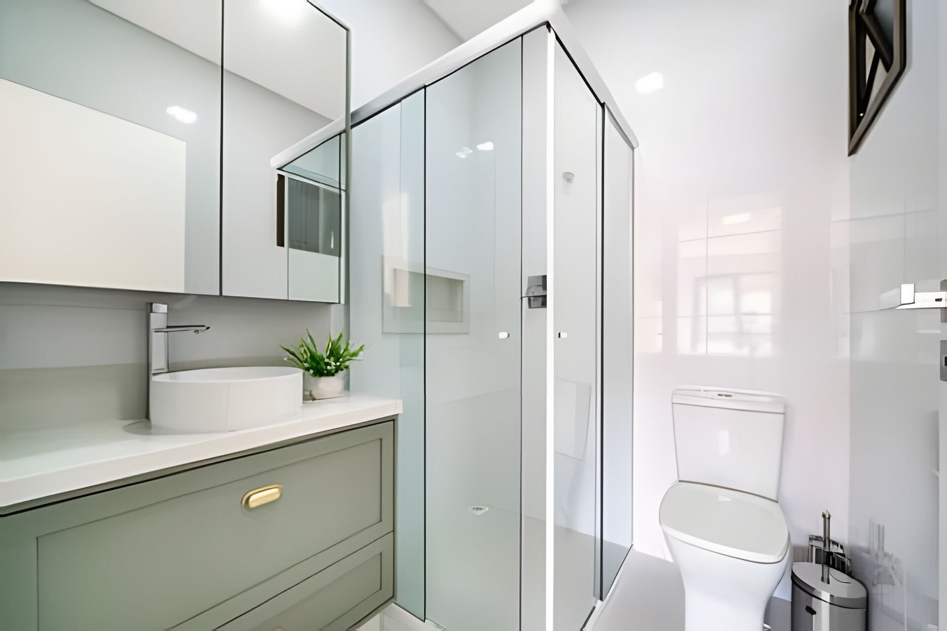 A modern bathroom with a glass shower enclosure, a white toilet, and a vanity with a sink and mirror.