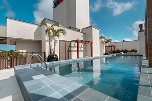 Una piscina con superficie de agua azul cristalina, rodeada de una terraza empavedada.
