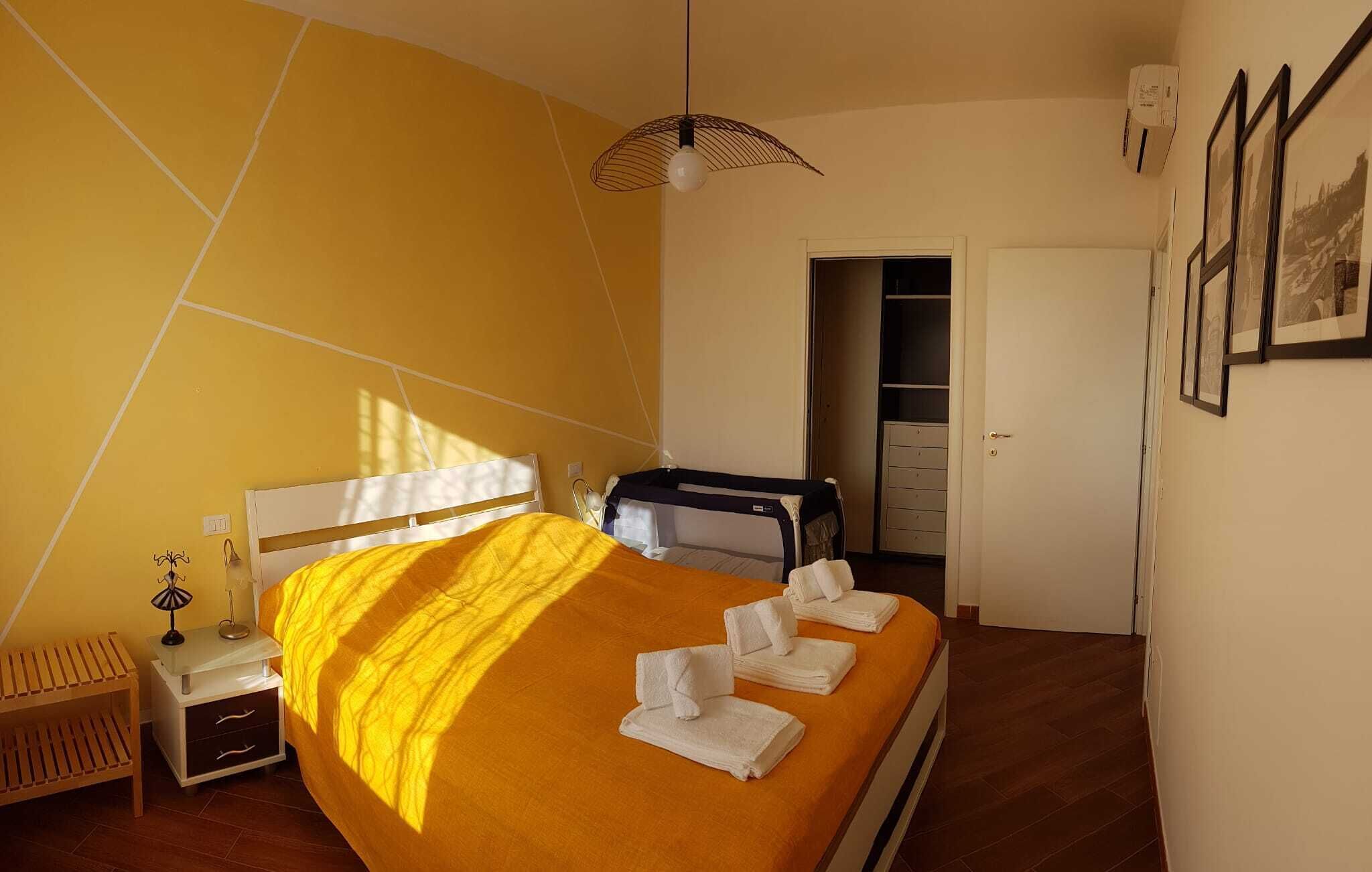 Une chambre d’hôtel avec un lit, une table de chevet, une lampe, une armoire et une porte.