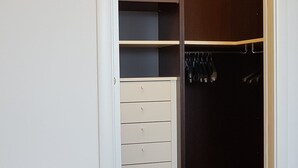 A walk-in closet with open shelves, a wooden bench, and a dark closet door. - CASA MIA Guesthouse (Firenze)
