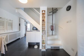 A modern kitchen with a built-in bookshelf, a microwave, and a staircase leading to another level. - London Home for 6 Plaistow Area - Transport Links (London)
