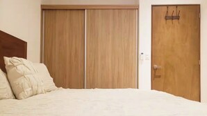 A bedroom with a bed, two wooden wardrobes, and a door with a handle.