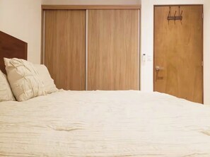 A bedroom with a bed, two wooden wardrobes, and a door with a handle. - Ipana (Playa del Carmen)