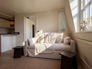 Ein modernes Wohnzimmer mit einer Couch, einem Couchtisch und Blick auf die Küche.