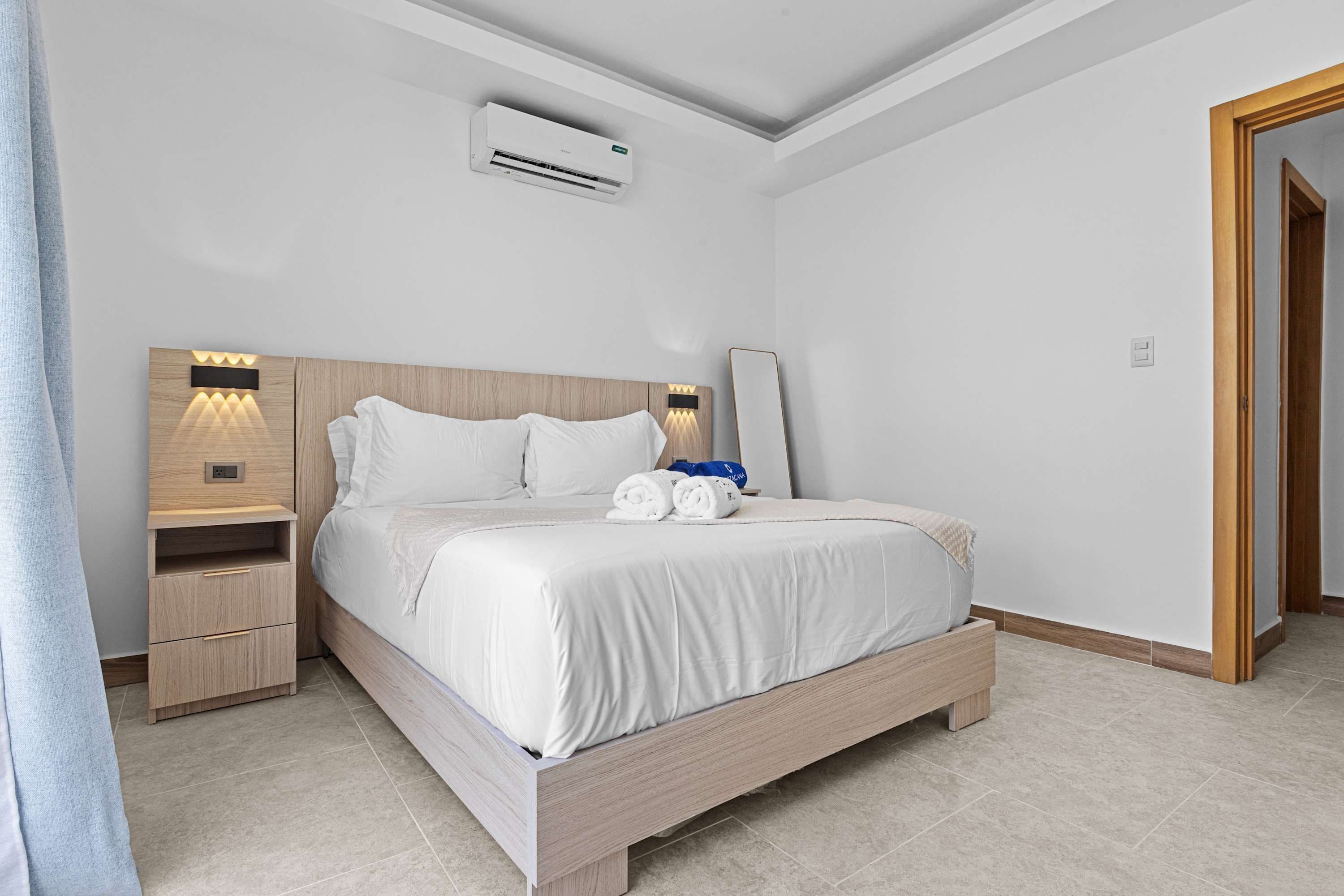 Ein Hotelzimmer mit einem Bett, Nachttischen, einer Klimaanlage und einer Tür.