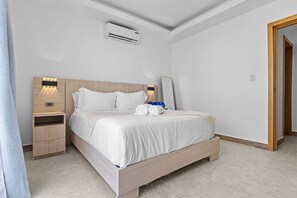 Ein Hotelzimmer mit einem Bett, Nachttischen, einer Klimaanlage und einer Tür.