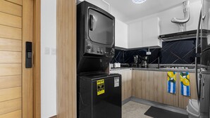 Una cucina compatta con forno a microonde integrato, frigorifero e piano cottura.