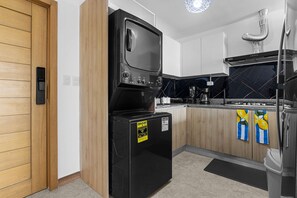 A compact kitchen with a built-in microwave, a refrigerator, and a stove. - NOK Caribbean 1BR Retreat By Vistacana (Punta Cana)