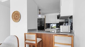Una cucina moderna con un bancone in legno, due sgabelli da bar e un elemento decorativo a parete.