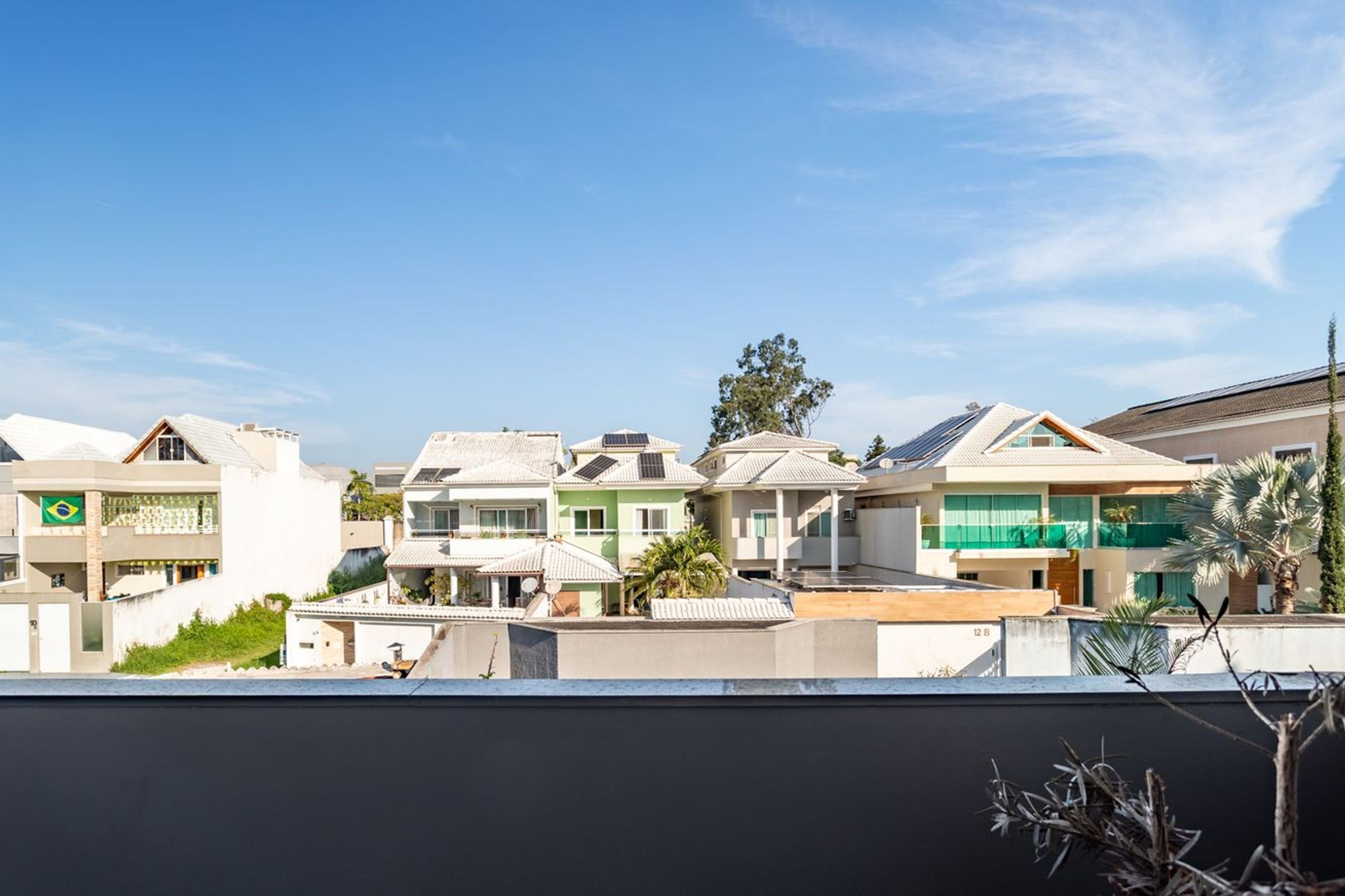 Um bairro residencial com várias casas, algumas equipadas com painéis solares, sob um céu azul e claro.
