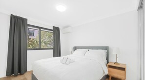 Una camera d'albergo moderna e pulita, con un letto, una lampada da comodino e una finestra con tende.