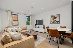 A modern living room with a sofa, coffee table, and dining area with chairs. - 2-bed 1 Bath Sleeps 4 Putney Near Thames (London)