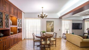 A dining area with a wooden table and chairs, a chandelier, and a large painting on the wall. - Elegant Spacious Apartment in Rhodes With Balcony (Rhodes)