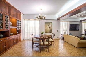 A dining area with a wooden table and chairs, a chandelier, and a large painting on the wall. - Elegant Spacious Apartment in Rhodes With Balcony (Rhodes)