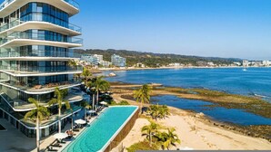 Ein mehrstöckiges Hotel mit Pool und Blick auf den Strand.