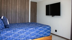 Ein Schlafzimmer mit einem Bett, einem an der Wand montierten Fernseher und Holzvertäfelung.