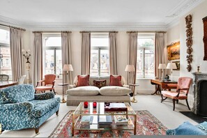 Ein geräumiges Wohnzimmer mit einer großen Couch, zwei Sesseln, einem Couchtisch und einem Kamin.