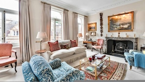 A spacious living room with a fireplace, a sofa set, a coffee table, and a view of the street. - Elegant Mayfair Home Central AC Mount Street (London)