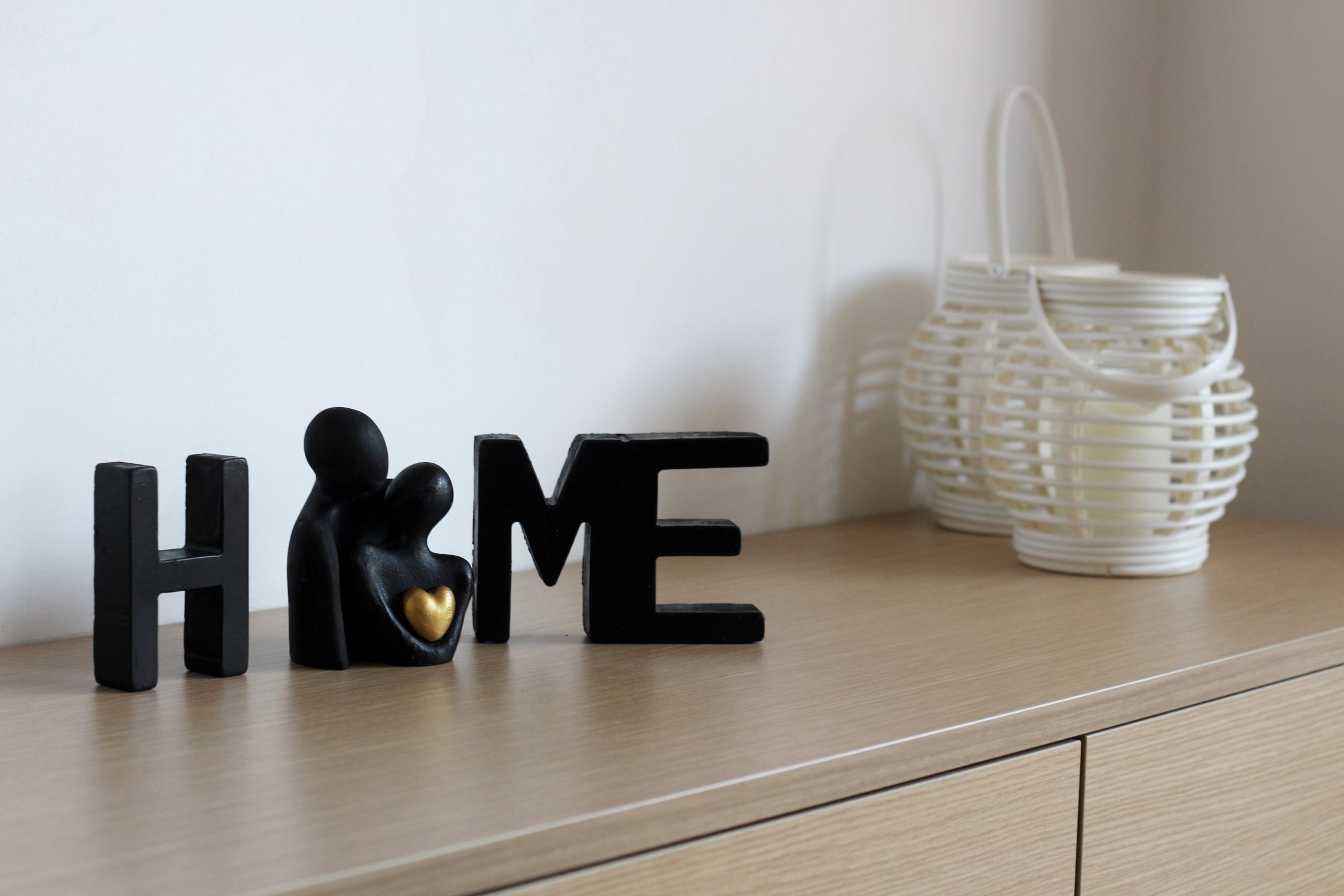 A wooden surface with black letter-shaped objects spelling 'HOME' and a small figurine.