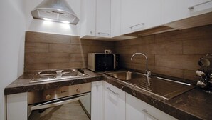 A modern kitchen with a built-in microwave, stainless steel sink, and a range hood. - Colosseo Fori Imperiali Apartment (Rome)