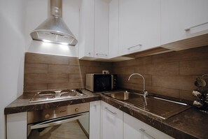 A modern kitchen with a built-in microwave, stainless steel sink, and a range hood. - Colosseo Fori Imperiali Apartment (Rome)