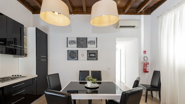 A modern kitchen with a dining area, black chairs, a glass table, and pendant lights. - San Francesco Ripa 3 - Trilussa 3BR Group Family Home (Rome)
