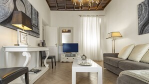 A modern living room with a flat-screen TV, a white coffee table, a grey sofa, and a dining table with chairs. - San Francesco Ripa 3 - Trilussa 3BR Group Family Home (Rome)