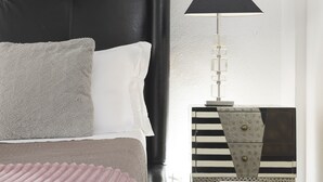 A bed with a grey pillow and white sheets, a black lamp on a side table, and a striped pattern on the wall. - San Francesco Ripa 3 - Trilussa 3BR Group Family Home (Rome)