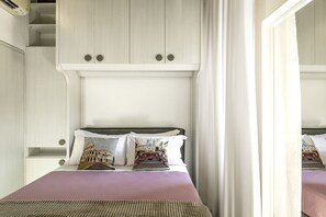 A bedroom with a bed, pillows, a headboard, and a mirror. - San Francesco Ripa 4 - Lorenza 3BR Group Family Home (Rome)