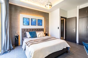 Un dormitorio moderno con una cama grande, un cabecero y tres cuadros enmarcados en la pared.