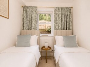 A bedroom with two beds, a window with curtains, a radiator, and a small table. - Perfect Booking Bright 2 Bed Maisonette in Bath (Bath)