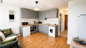 A compact kitchen with grey cabinets, a microwave, a dishwasher, and a washing machine. - Perfect Booking Bright 2 Bed Maisonette in Bath (Bath)