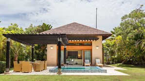 Ein modernes Haus mit Pool, Sitzgelegenheiten im Freien und einer überdachten Terrasse.