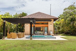 Ein modernes Haus mit Pool, Sitzgelegenheiten im Freien und einer überdachten Terrasse.