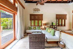 A room with a sofa, a wicker chair, and a television. - Stylish Bungalow at Green Village With Pool Ab3 (Punta Cana)
