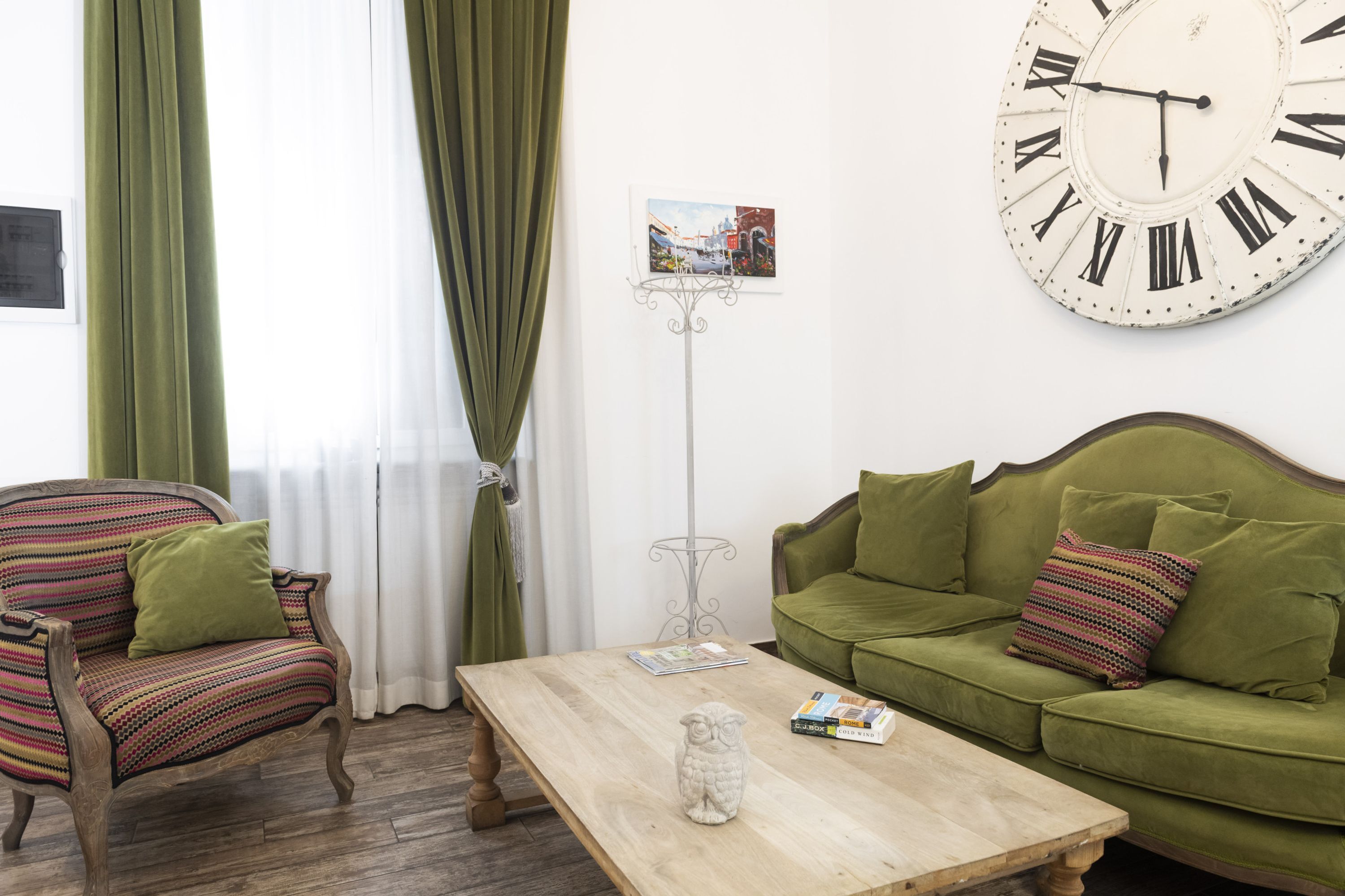 Una habitación con un sofá verde, una mesa de centro de madera y un reloj de pared grande.