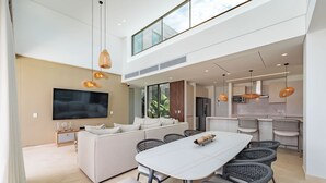 A modern living space with a dining area, a sofa set, a flat-screen TV, and a kitchen area. - Modern 4 Bedroom Villa With Tropical Vibes in Baru (Cartagena)