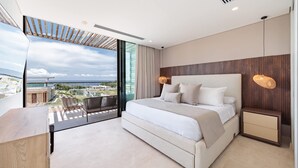 A modern bedroom with a large bed, a nightstand, and a view of the city. - Modern 4 Bedroom Villa With Tropical Vibes in Baru (Cartagena)