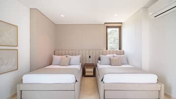 A modern bedroom with two beds, a nightstand, and a window.