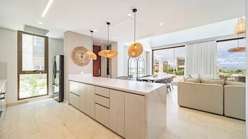 A modern kitchen with a central island, pendant lights, and a view to the outside.