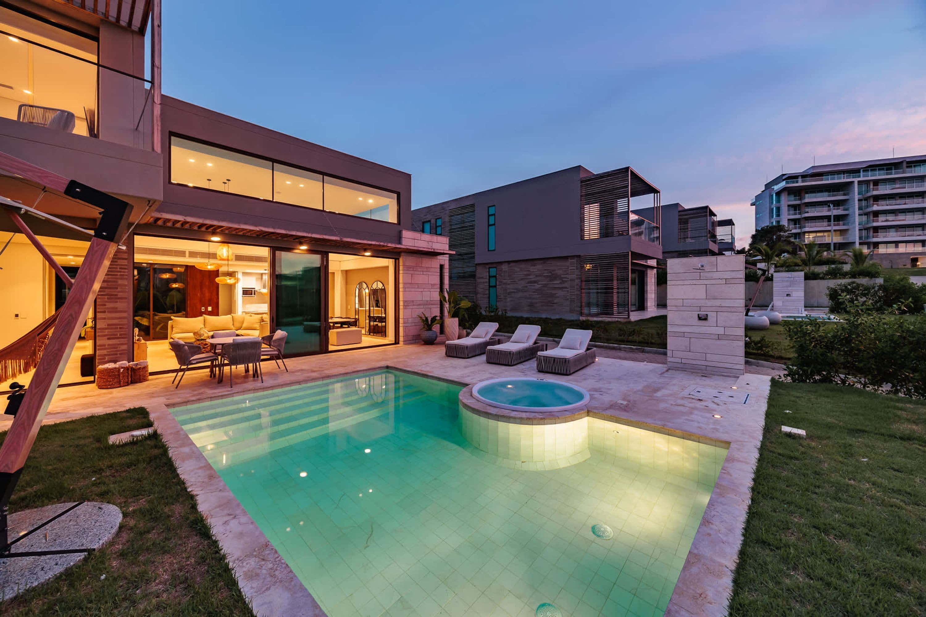A modern house with a swimming pool, outdoor seating, and a well-lit patio area.
