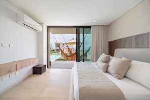 A modern bedroom with a large bed, a built-in bench, and a view of a swimming pool and buildings. - Modern 4 Bedroom Villa With Tropical Vibes in Baru (Cartagena)