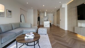 Ein modernes Wohnzimmer mit einem grauen Sofa, einem runden Couchtisch und einem Flachbildfernseher.