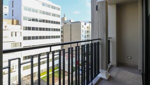 Ein Balkon mit Blick auf eine Skyline, darunter ein Gebäude mit einer Flagge.